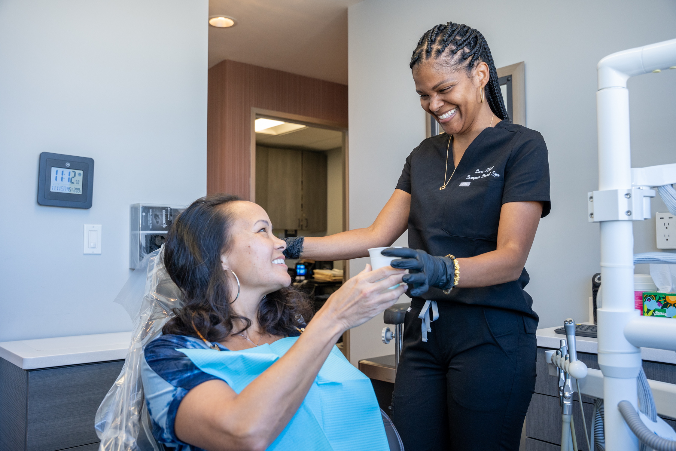 Dana L., a Registered Dental Assistant of Derrick Thompson DDS INC is giving a cup of water to a woman patient - Dentist Los Angeles Dana L., a Registered Dental Assistant of Derrick Thompson DDS INC is giving a cup of water to a woman patient - Dentist Los Angeles