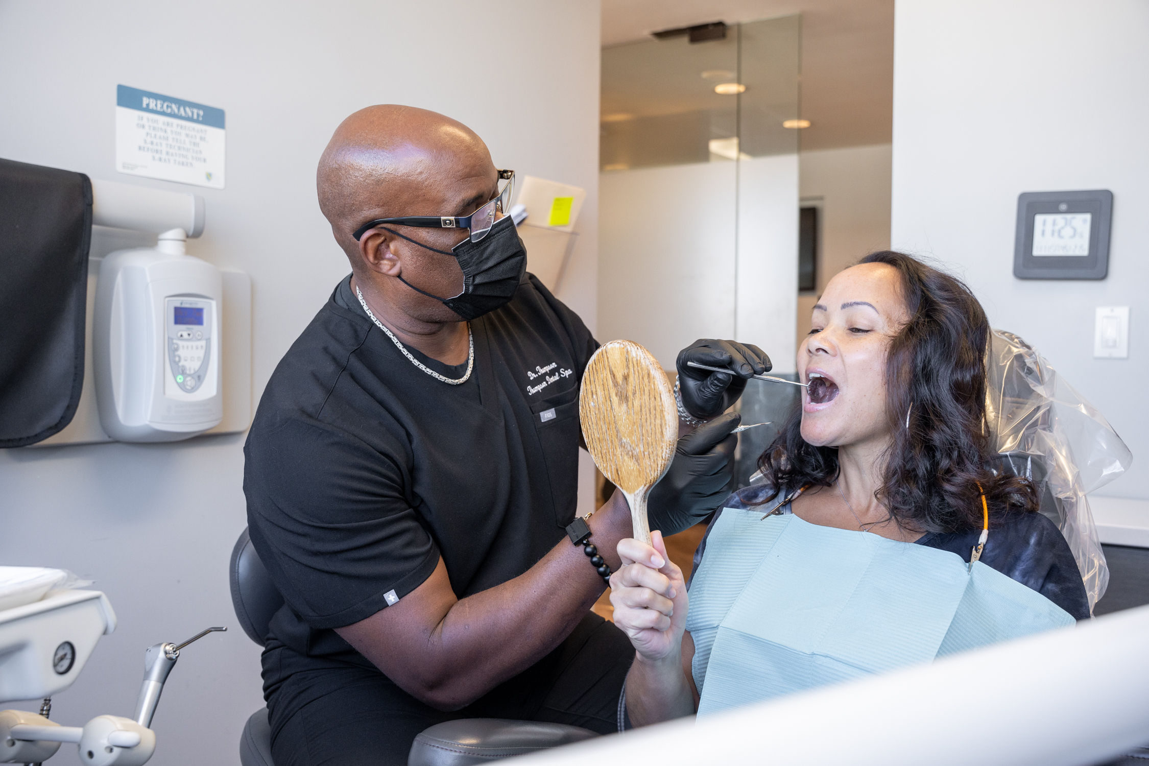 Dr. Derrick L. Thompson, DDS is examining a lady patient's mouth for possible dental treatment - Dentist Los Angeles Dr. Derrick L. Thompson, DDS is examining a lady patient's mouth for possible dental treatment - Dentist Los Angeles