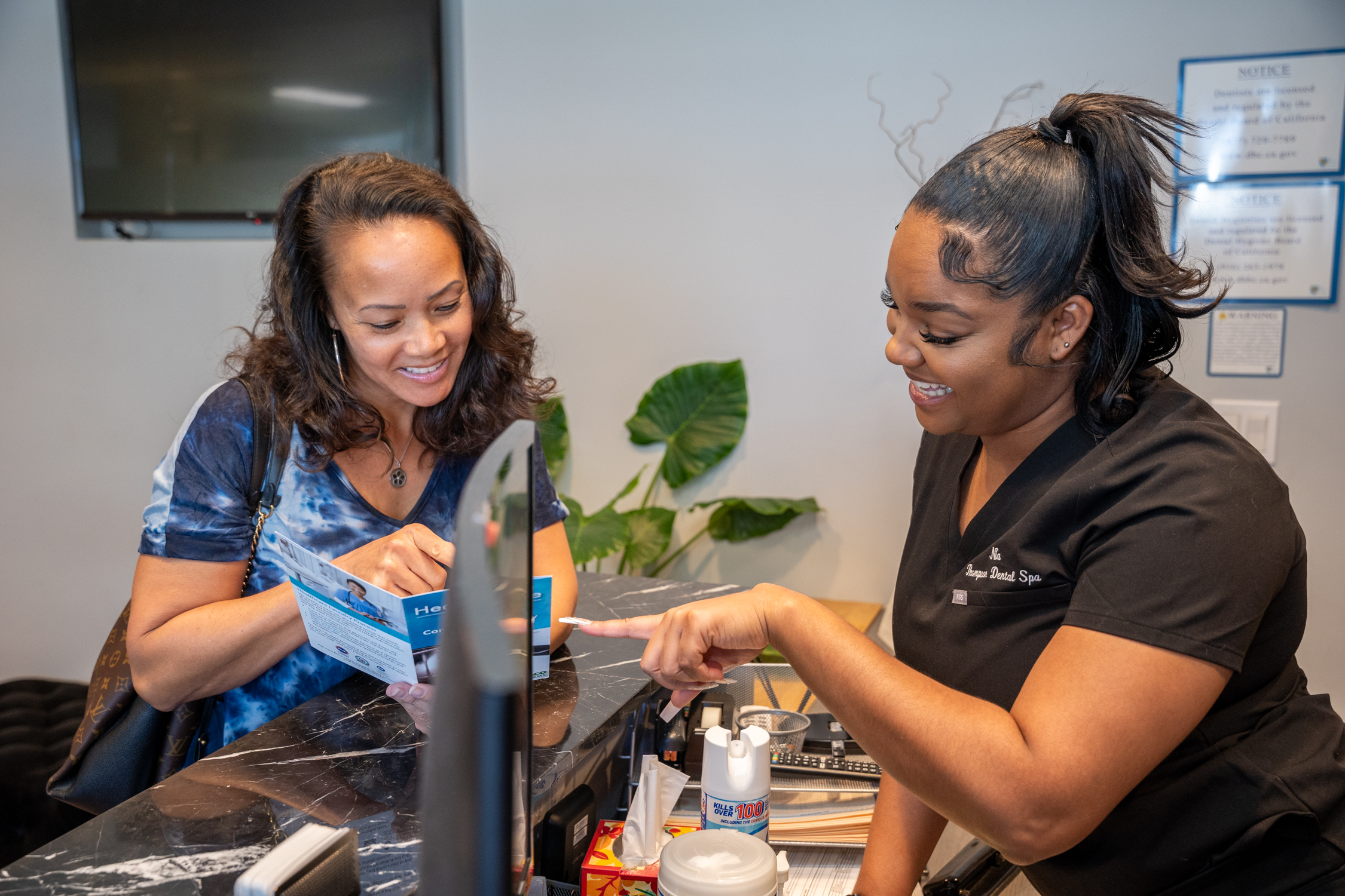 Nia T., the Administrative Assistant of Derrick Thompson DDS INC is explaining some dental options to a lady customer - Dentist Los Angeles Nia T., the Administrative Assistant of Derrick Thompson DDS INC is explaining some dental options to a lady customer - Dentist Los Angeles